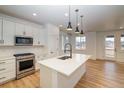 Modern kitchen with stainless steel appliances and central island with sink and faucet at 8633 Middle Fork St, Littleton, CO 80125