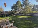 Spacious backyard with lush green grass, mature trees, and a wooden swing set at 4609 S Kalispell Way, Aurora, CO 80015
