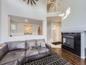Bright living room featuring a fireplace, open staircase, and comfortable leather sofa with hardwood flooring at 11811 Lewiston St, Commerce City, CO 80022