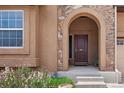 Close-up of front door entrance featuring stone archway, wooden door, and well-maintained landscaping at 15616 Soo Line Way, Monument, CO 80132