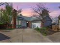 Charming single-Gathering home with brick accents, a large driveway, and mature trees under a beautiful sunset at 772 Ivywood Ct, Highlands Ranch, CO 80126