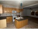 Functional kitchen featuring wood cabinets, an island with sink, and white appliances at 5500 Dacono Ct, Byers, CO 80103