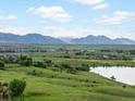Scenic aerial view of lush green landscapes, a tranquil lake, and majestic mountains in the distance at 10954 W 100Th Way, Broomfield, CO 80021
