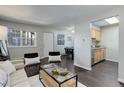 Modern living room featuring wood flooring, comfortable seating, and access to a kitchen and dining area at 5873 S Prince St # 117C, Littleton, CO 80120