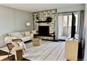 Cozy living room with a stone fireplace, comfortable seating, neutral rug, and lots of natural light coming from the glass door at 7255 E Quincy Ave # 309, Denver, CO 80237