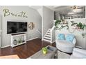 Relaxing living room with dark wood floors, stairs, and large television is perfect for entertaining at 8199 Welby Rd # 1102, Denver, CO 80229