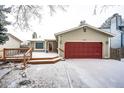 This house has a large red garage door, snow-covered driveway, and wooden deck area at 4274 S Fundy Way, Aurora, CO 80013