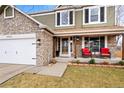 Close up of front porch with chairs and stone facade with attached garage of a beautiful two-story home at 2924 E 116Th Pl, Thornton, CO 80233