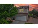 Two-story home with tan siding, new brown shingle roof and inviting exterior lighting at 7270 Marmot Ridge Pl, Littleton, CO 80125