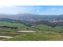 Beautiful mountain view overlooking rolling green hills with scattered trees and rock formations at 7270 Marmot Ridge Pl, Littleton, CO 80125