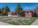 A single-story brick home with a manicured lawn and mature trees creating a cozy aesthetic at 8325 Elati St, Denver, CO 80221
