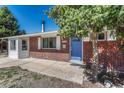 Inviting front entry with a brick facade, a blue front door and a well maintained lawn at 8325 Elati St, Denver, CO 80221