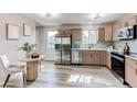 Eat-in kitchen featuring stainless appliances, wood cabinets, modern lighting, and ample sunlight at 280 Birch St, Bennett, CO 80102