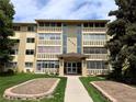 Inviting condo complex featuring a manicured lawn, mature trees, and charming architectural details at 9155 E Center Ave # 4B, Denver, CO 80247