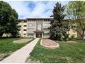 Inviting condo complex featuring a manicured lawn, mature trees, and charming architectural details at 9155 E Center Ave # 4B, Denver, CO 80247