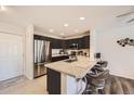 Open concept kitchen with black cabinets, stainless appliances and granite counters plus eat-in bar seating at 5075 Garrison St # 3, Wheat Ridge, CO 80033