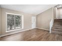 A living room featuring wood floors, stairs to second level, a large window, and a white front door at 19876 E Brunswick Dr, Aurora, CO 80013