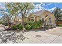 Exterior view of a tan condo complex with well-maintained landscaping and mature trees at 8843 W Phillips Dr, Littleton, CO 80128