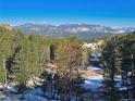 Breathtaking mountain view with snow capped peaks overlooking a lush forest and neighborhood at 6241 Kilimanjaro Dr, Evergreen, CO 80439
