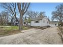 View of the home's side featuring a driveway that leads to a detached garage and tidy landscaping at 2481 Garrison St, Lakewood, CO 80215