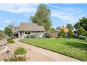 Landscaped front yard featuring a lush green lawn, pathway, and surrounding greenery at 2595 S Irving St, Denver, CO 80219