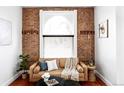 Stylish living room showcasing an exposed brick wall, a comfortable sofa, and ample natural light at 2909 Glenarm Pl, Denver, CO 80205
