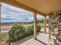 Relaxing front porch view overlooking the street with comfortable seating and stone pillars at 4118 Desert Ridge Cir, Castle Rock, CO 80108