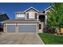Two-story home with a three car garage, stone accents, and mature lawn at 331 Las Lomas St, Brighton, CO 80601