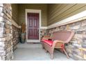 Covered front porch with a wood chair and a decorative vase sitting next to the front door at 3936 Costillo Ct, Brighton, CO 80601