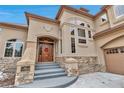 Gorgeous home entrance with a beautiful solid wood door, stone accents, and well-manicured landscaping at 9132 Scenic Pine Dr, Parker, CO 80134