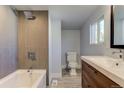 Bathroom features a bathtub, tile surround, modern vanity, and a bright window at 915 N Irving St, Denver, CO 80204