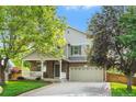 Inviting two-story home with stone accents, a covered porch, a well-manicured lawn and a two car garage at 14794 Vine St, Thornton, CO 80602