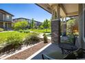 Inviting covered porch with brick pillars, outdoor seating, and views of the lush green space at 11033 E 28Th Pl, Denver, CO 80238