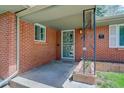 Inviting covered front porch featuring a secure screen door and classic brick accents at 3090 S High St, Denver, CO 80210