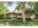 Beautifully landscaped home with large tree, manicured lawn, and classic brick exterior at 1695 E Eastman Ave, Englewood, CO 80113