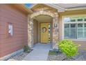 Inviting entryway featuring a stone archway, yellow door with wreath, and decorative landscaping at 8611 Gold Peak Dr # D, Highlands Ranch, CO 80130