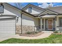 Home featuring stone accents, a two-car garage and manicured front yard at 15901 W 66Th Pl, Arvada, CO 80007