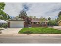 Charming single-story brick home with a well-manicured lawn and mature trees, complemented by a welcoming front porch at 13472 E Dakota Ave, Aurora, CO 80012