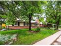 Charming tan home with brick, chimney, solar panels, tidy yard, and for sale sign at 1810 S Kearney St, Denver, CO 80224