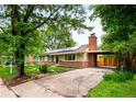 Charming tan home with brick, chimney, solar panels, tidy yard, long driveway, and covered car port at 1810 S Kearney St, Denver, CO 80224