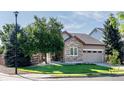 Beautiful home exterior featuring stone accents, a green lawn, mature trees, and an attached two-car garage at 10482 Billings St, Commerce City, CO 80022