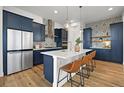 Modern kitchen features a large island with seating, navy cabinets, and stainless steel appliances at 21440 E 61St Dr, Aurora, CO 80019
