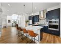 Modern kitchen boasts navy cabinets, a waterfall island with seating, and a decorative backsplash at 21440 E 61St Dr, Aurora, CO 80019