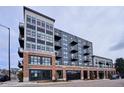 Modern apartment building featuring brick and gray siding, multiple balconies, and convenient garage access at 3500 S Corona St # 409, Englewood, CO 80113