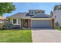 Home with a two-car garage, bay window, brick details, and a neatly kept lawn at 7054 S Flower Ct, Littleton, CO 80128