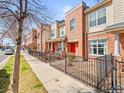 Street view of modern townhomes with brick and siding exteriors and black metal fences at 7323 Lowell Blvd, Westminster, CO 80030