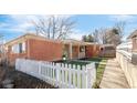 Beautifully maintained brick home with a white picket fence, green grass, and a welcoming facade at 1476 W Dakota Ave, Denver, CO 80223