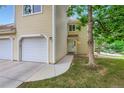 This townhome exterior features tan siding, an attached garage, and a well-maintained lawn at 461 S Kalispell Way # D, Aurora, CO 80017