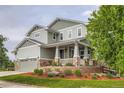 Beautiful two-story home featuring a covered porch, manicured lawn with mulch, and a convenient two-car garage at 23503 E Minnow Dr, Aurora, CO 80016