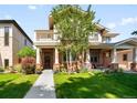 Charming two-story home with a brick facade, balcony, covered porch, manicured lawn and flower beds at 1265 S Sherman St, Denver, CO 80210